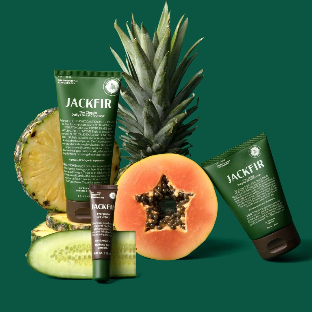 Jackfir Cleanser + Moisturizer + Eye Cream Set with sliced pineapple, papaya, and cucumber arranged around green tubes