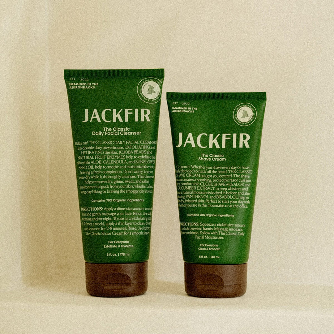 Jackfir Cleanser + Shave Cream Duo tubes standing side by side, dark green packaging with brown caps, back labels facing forward