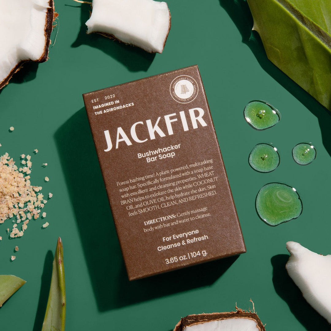 Jackfir The Bushwhacker Bar Soap 3-Pack box flat lay with water droplets, coconut pieces, and wheat bran scattered