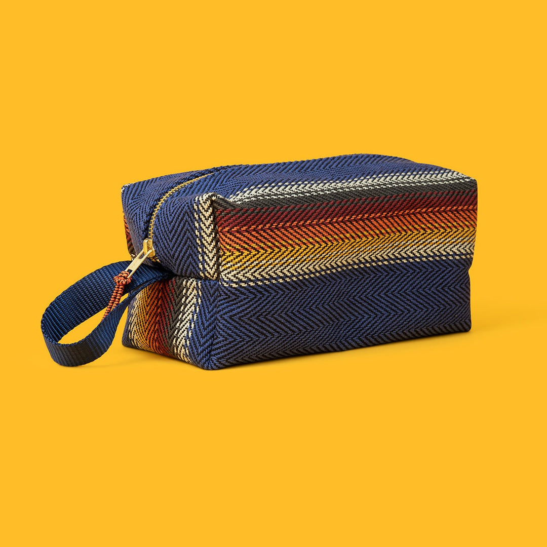 Jackfir The Clean Cowboy® Toiletry Kit zipped closed showing striped navy, rust, and yellow herringbone pattern