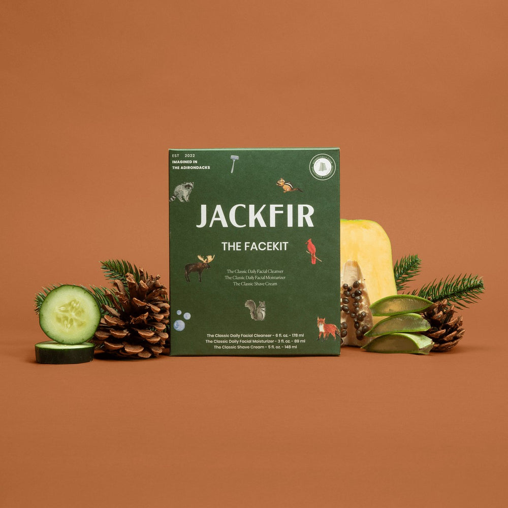 Jackfir The Facekit green box standing upright surrounded by pinecones, cucumber slices, and pine sprigs