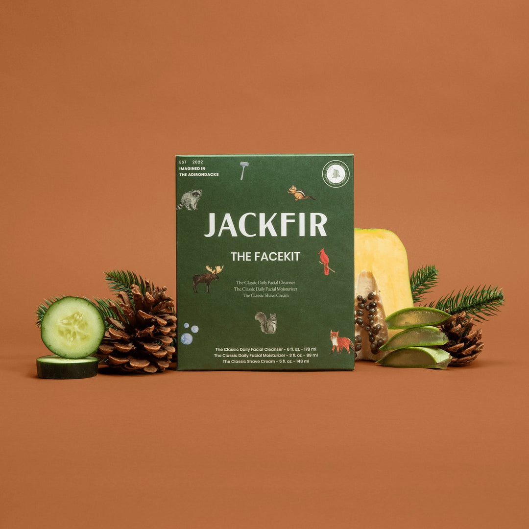Jackfir The Facekit green box standing upright surrounded by pinecones, cucumber slices, and pine sprigs